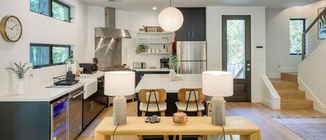 A modern kitchen with a central island, built-in appliances, and a dining area with two chairs and a table.
