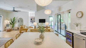 A modern living room with a dining area, a ceiling fan, a large pendant light, a flat-screen TV, and a kitchen area with a refrigerator. - Mill Creek by Avantstay Modern Design, Patio, Hot Tub (Healdsburg)