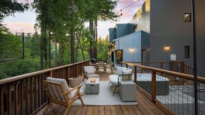 A deck with outdoor furniture, a grill, and a view of a forested area. - Mill Creek by Avantstay Modern Design, Patio, Hot Tub (Healdsburg)