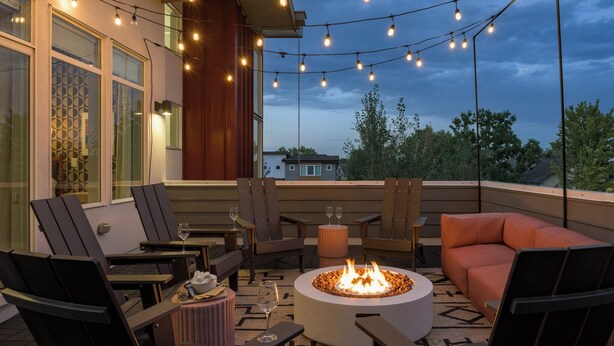 Un espacio al aire libre con sillas, una mesa y un hogar para la chimenea.