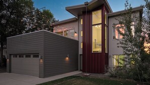 Una casa moderna de dos pisos con garaje, ventanas amplias y luces colgantes.