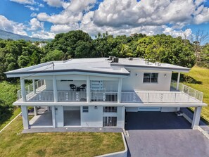 A two-story house with a covered porch, a garage, and a fenced yard. - Unique Top Caribbean Private Retreat (LUQUILLO)