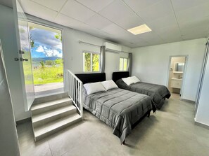 A bedroom with two beds, a bathroom, and a balcony with a view of greenery. - Unique Top Caribbean Private Retreat (LUQUILLO)