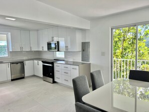 Enjoy meals in the kitchen with a stainless steel stove, microwave, and large window offering a view of lush greenery.