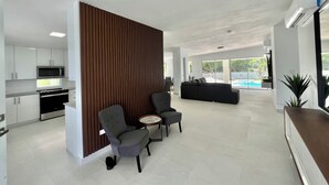 A modern interior with a kitchen, seating area, and a view of an outdoor pool.