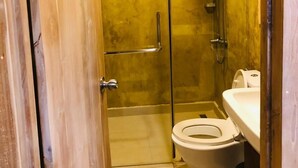 A small, compact bathroom with a shower, toilet, and sink.
