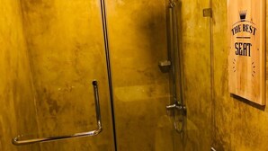 A bathroom with a glass shower enclosure, a toilet, and a vanity with a mirror.