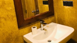 A bathroom with a white sink, a mirror with a wooden frame, and a yellow wall.