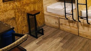A compact, wooden-themed bathroom with bunk beds, a small table, and a mirror.