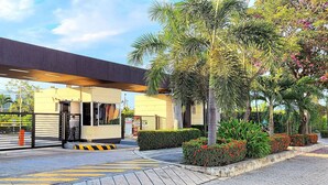 Un edificio moderno con un acceso cubierto, un cartel que dice "Cabo Verde Praia" y un camino pavimentado que conduce a la entrada.