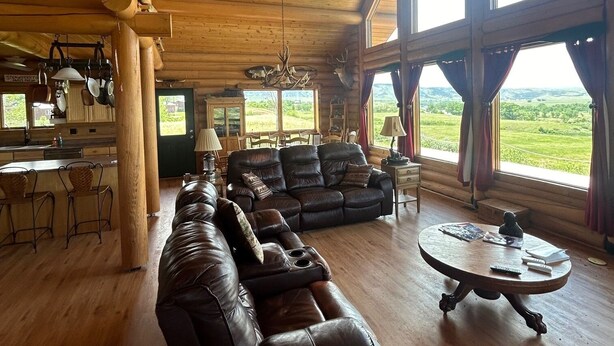 Ein geräumiges Wohnzimmer mit einer großen Ledersofa, einem runden Couchtisch und einem Essbereich mit Holzsesseln.