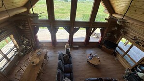 Eine geräumige Hütte mit hoher Decke, großen Fenstern, einem Essbereich, einem Wohnzimmer mit einer Couch und einem Kamin.