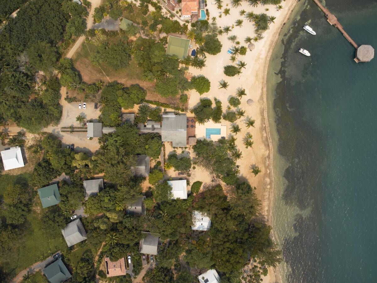 Vista aérea de una zona costera con casas, una playa y barcos.