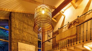 Een ruime woonkamer met een stenen openhaard, een hoge plafond en een balkon.