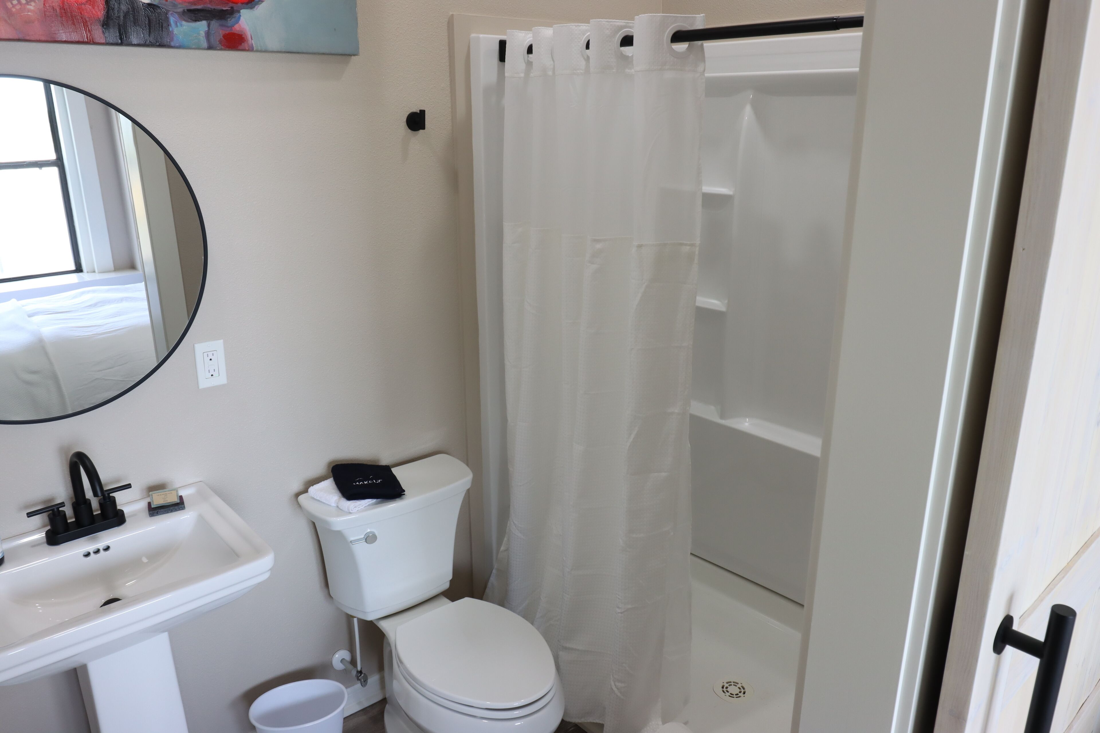 Un baño con lavamanos, inodoro y cortina de ducha blancos.