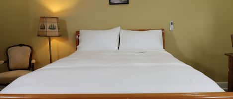 Una cama con sábanas blancas impecables en una habitación con cabecera de madera. Hay tres cuadros enmarcados en la pared sobre la cama.