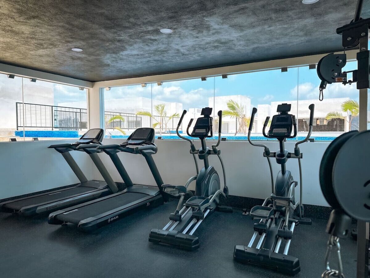 Una palestra con tapis roulant, macchinari ellittici e una panca per pesi.