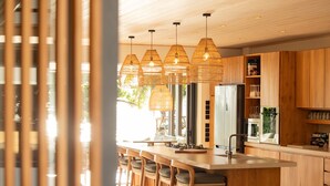 Eine moderne Küche mit Holzausstattung, einer zentralen Kochinsel mit Barhocker und hängenden Korblampen.