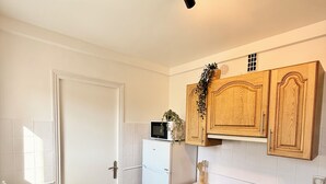 A kitchen with white cabinets, a built-in oven, a microwave, and a sink.