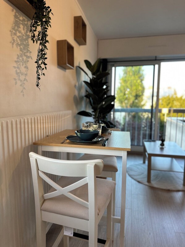A dining area with a white chair, a table with a bowl and plates, and a potted plant.