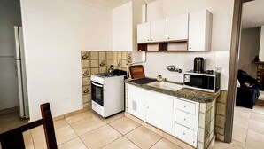 A compact kitchen with a stove, microwave, and cabinets. - RentUp- Casa a pasos del Centro Cívico (San Carlos de Bariloche)