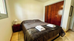 A bedroom with a bed, a nightstand, a wooden wardrobe, and a window. - RentUp- Casa a pasos del Centro Cívico (San Carlos de Bariloche)