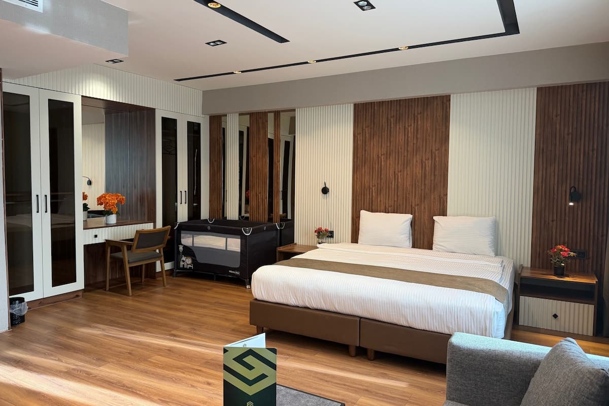 Ein modernes Hotelzimmer mit Bett, Schreibtisch, Stuhl und einem kleinen Tisch mit Blumenvase.