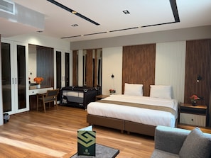 Quarto de hotel moderno com cama, escrivaninha, cadeira e uma pequena mesa com um vaso de flores.