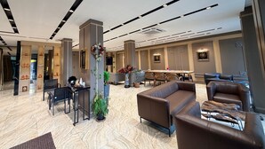 A modern lobby with a reception desk, seating area, and a large decorative column. - GRAND SAVCILI DELUX (Gaziantep)