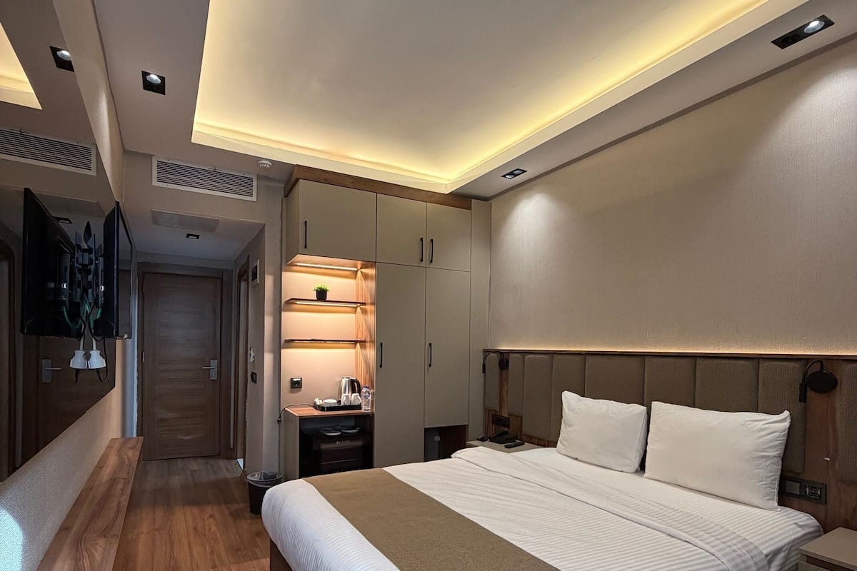 Ein modernes Hotelzimmer mit einem großen Bett, Nachttischen, einem Schreibtisch und einer Sitzecke.