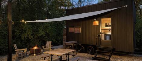 A rustic outdoor seating area with a fire pit, wooden furniture, and a covered patio.