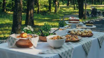 An outdoor dining area with tables set for a meal, surrounded by trees.