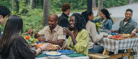 A group of people seated at checkered tables outdoors, enjoying a meal.