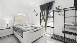 Un dormitorio moderno con cama, mesita de noche, armario y ventana con cortinas.