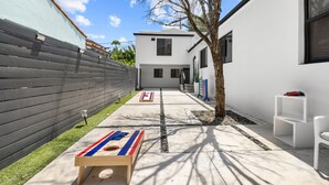 Un patio con una mesa de juego de hojalata, un banco de madera pequeño y una silla blanca.
