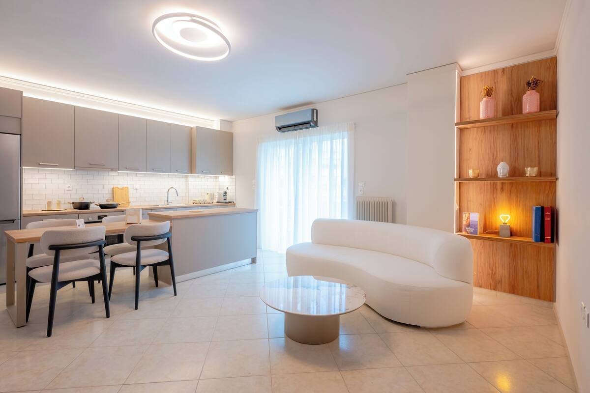 A modern kitchen with a dining area, a white sofa, and a coffee table.