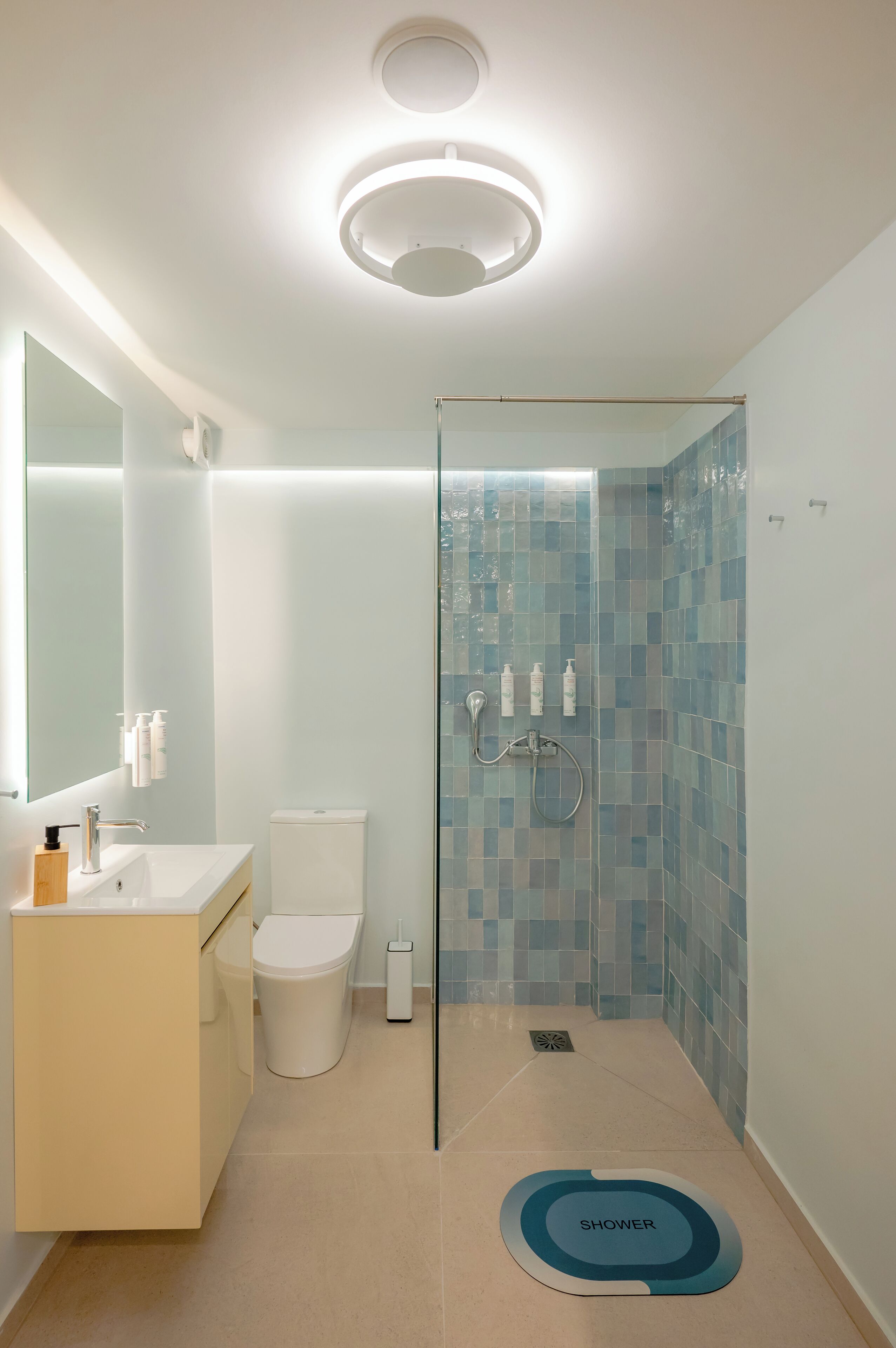Un baño moderno con cabina de ducha de vidrio, inodoro y lavamanos con espejo.