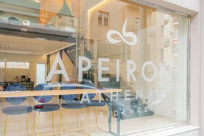 A hotel window with the name "APEIRON ATHENA RESIDENCES" and a view of the interior including a reception area with a counter and chairs. - Apeiron Athena Residences (Athens)