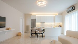 Uma cozinha moderna com armários brancos, forno embutido e uma área de jantar com mesa e cadeiras redondas.