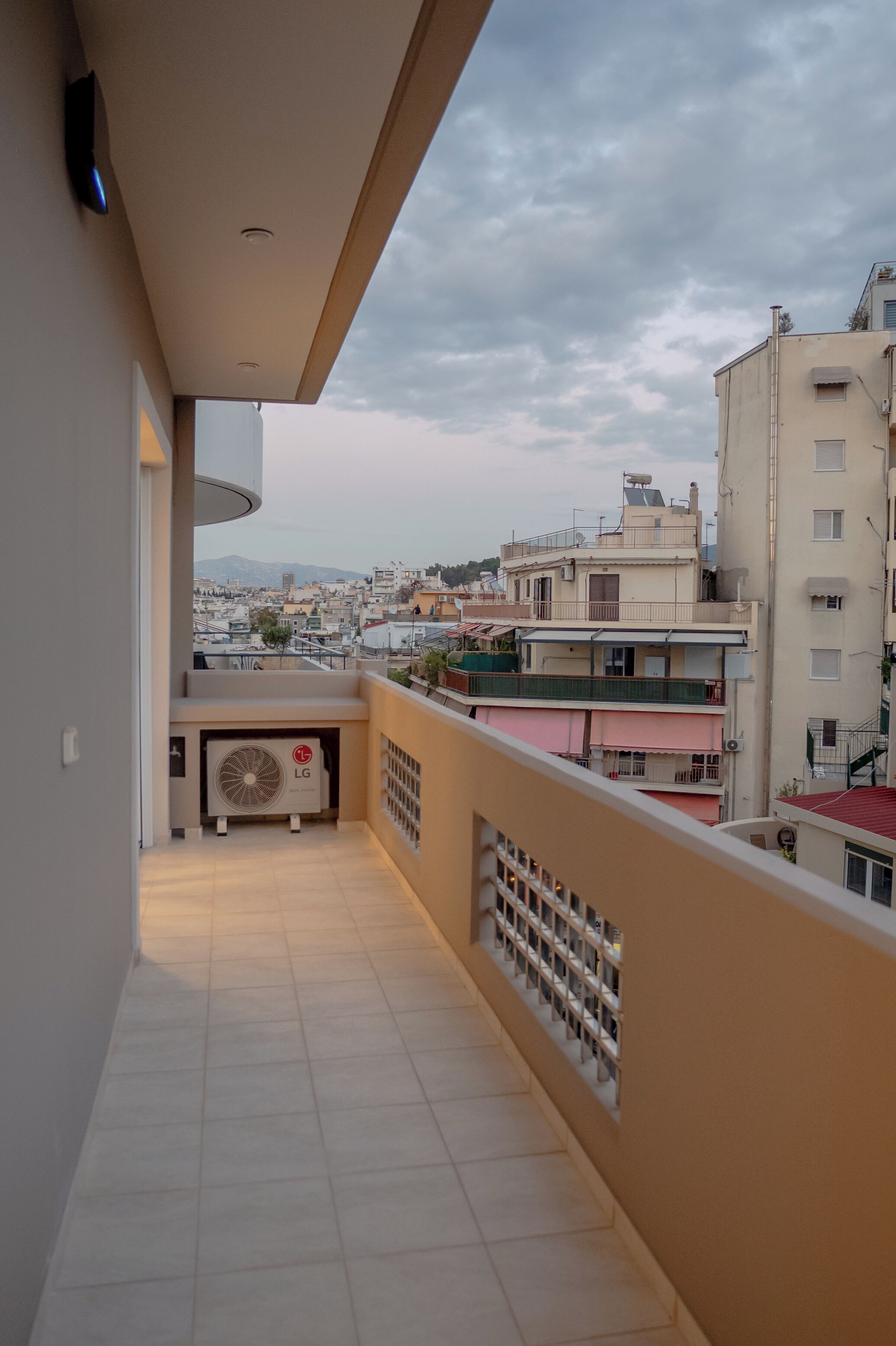 Un balcó amb vista a un paisatge urbà, un aire condicionat i un terra de rajola.