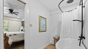 Une salle de bain avec une baignoire blanche, une douche et un ventilateur de plafond.