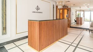 Een receptiebalie met een logo, houten paneeldecoratie en een kroonluchter.