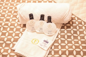 A neatly folded white towel with three bottles of PRADO hotel business shampoo and conditioner, and a small packet of PRADO alcohol gel. - Padom Businesse Hotel (Braganca Paulista)