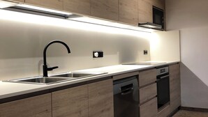 Una cocina moderna con armarios de madera, un lavamanos de acero inoxidable y un lavavajillas empotrado.