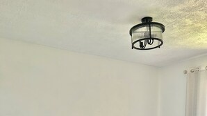 Une chambre bien rangée, avec un lit, des tables de chevet, une lampe et un luminaire suspendu.