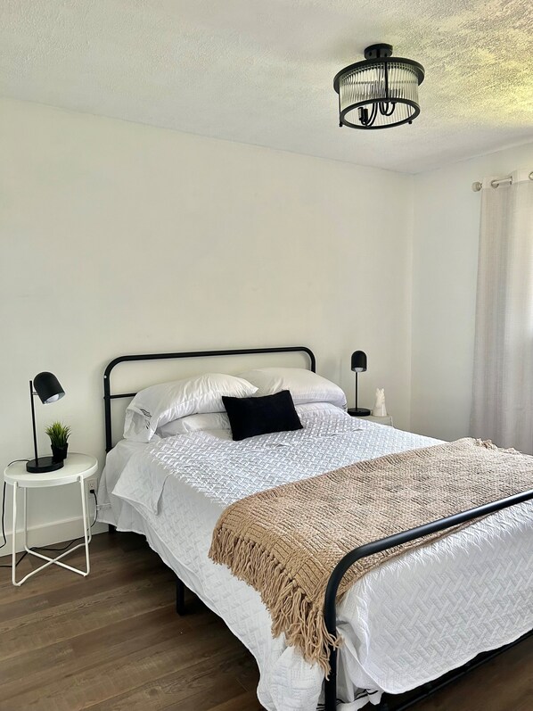 A neatly arranged bedroom with a bed, bedside tables, a lamp, and a hanging light fixture.