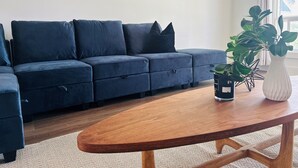 Un salon moderne avec un canapé bleu foncé, une table basse en bois et une plante en pot.