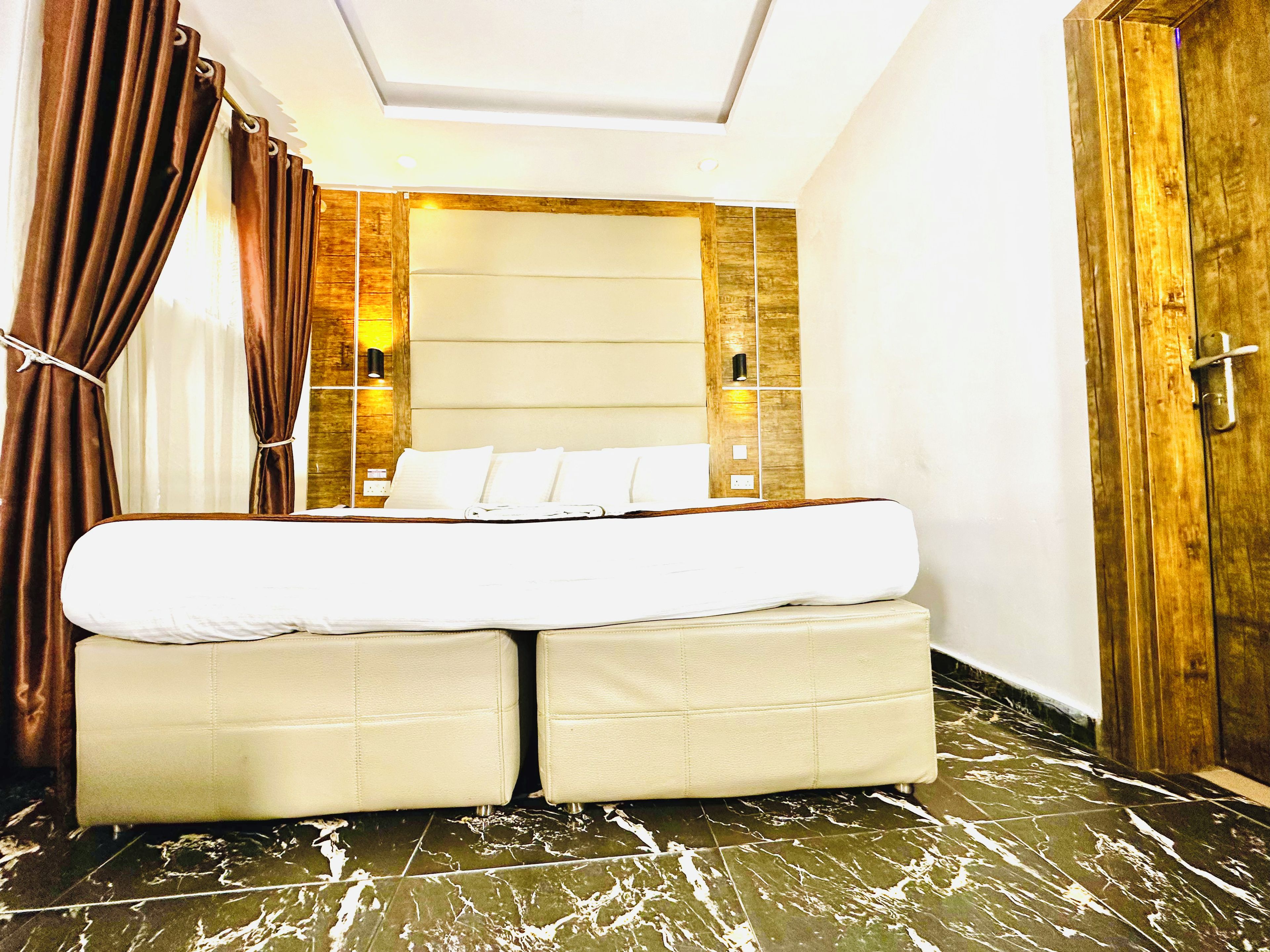 A bed with a headboard, a bedside table, and a wall-mounted light fixture.