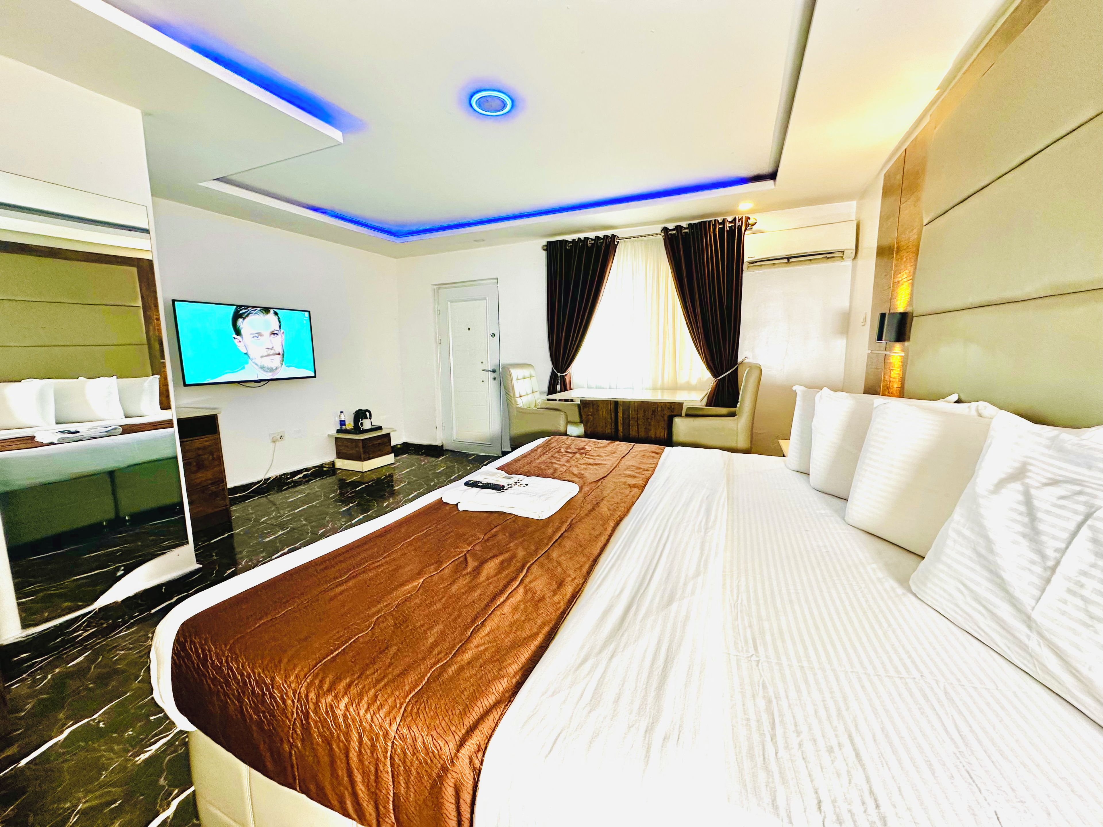 Una habitación de hotel con una cama grande, una televisión de pantalla plana, un escritorio y una silla.