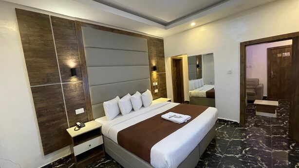A modern hotel room with a large bed, a nightstand, a mirror, and a marble floor. - PRESKEN HOTELS FAJODD4 (Lagos)